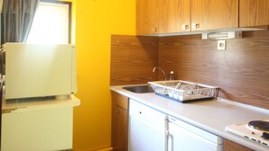 A compact kitchen with wooden cabinets, a white countertop, and a small sink. - Comfortable ski-in/ski-out apartment with panoramic view (Chamrousse)