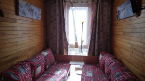 A cozy room with wooden walls, a patterned sofa, and a window with curtains.