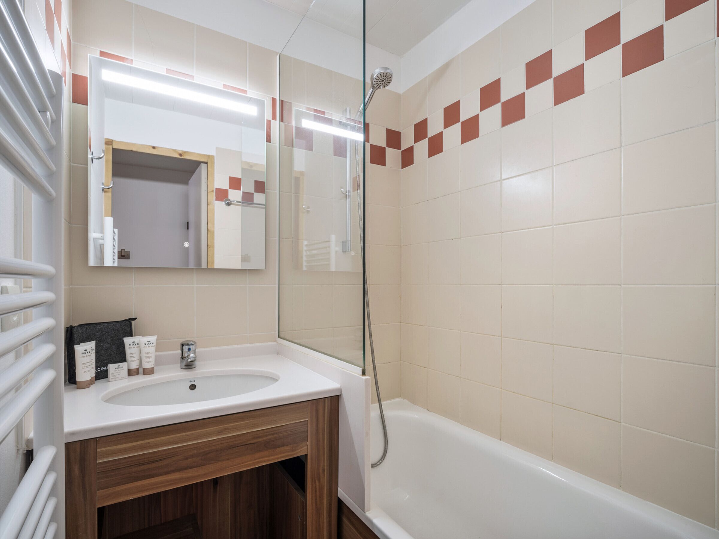 Baño con lavamanos, espejo y ducha.