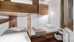 A bunk bed room with wooden headboard, a small bedside table, and a window with curtains. - Val Thorens: Modern 4 ppl apartment with parking and piste view (Val Thorens)