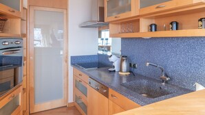 Eine moderne Küche mit Holzausstattung, einer Arbeitsplatte aus Granit und Edelstahlgeräten.