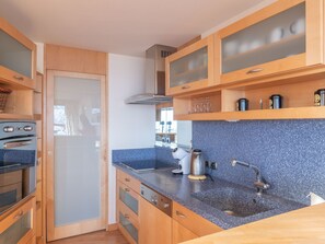 Eine moderne Küche mit Holzausstattung, einer Arbeitsplatte aus Granit und Edelstahlgeräten.
