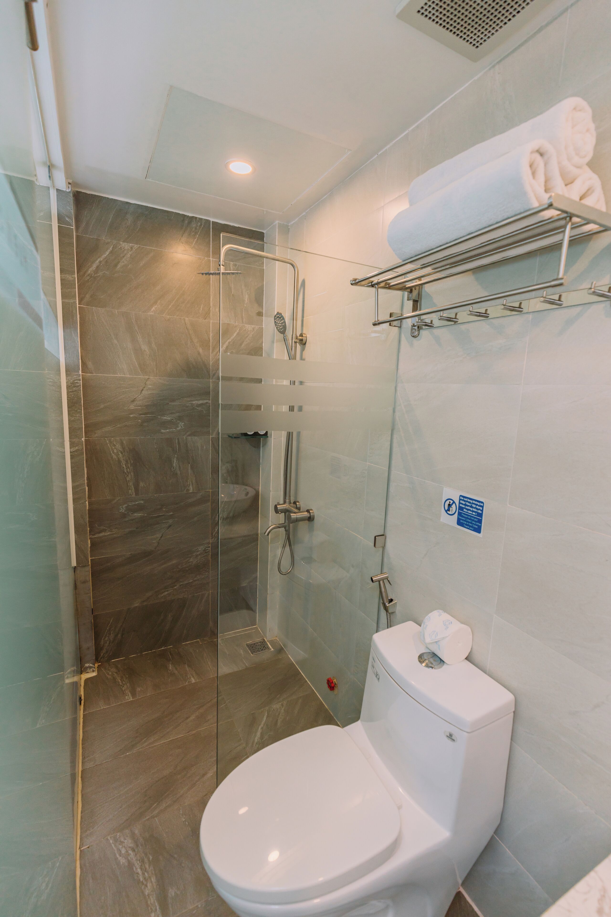 Ein modernes Badezimmer mit einer in Glas eingefassten Dusche, einer weißen Toilette und einem Handtuchhalter.