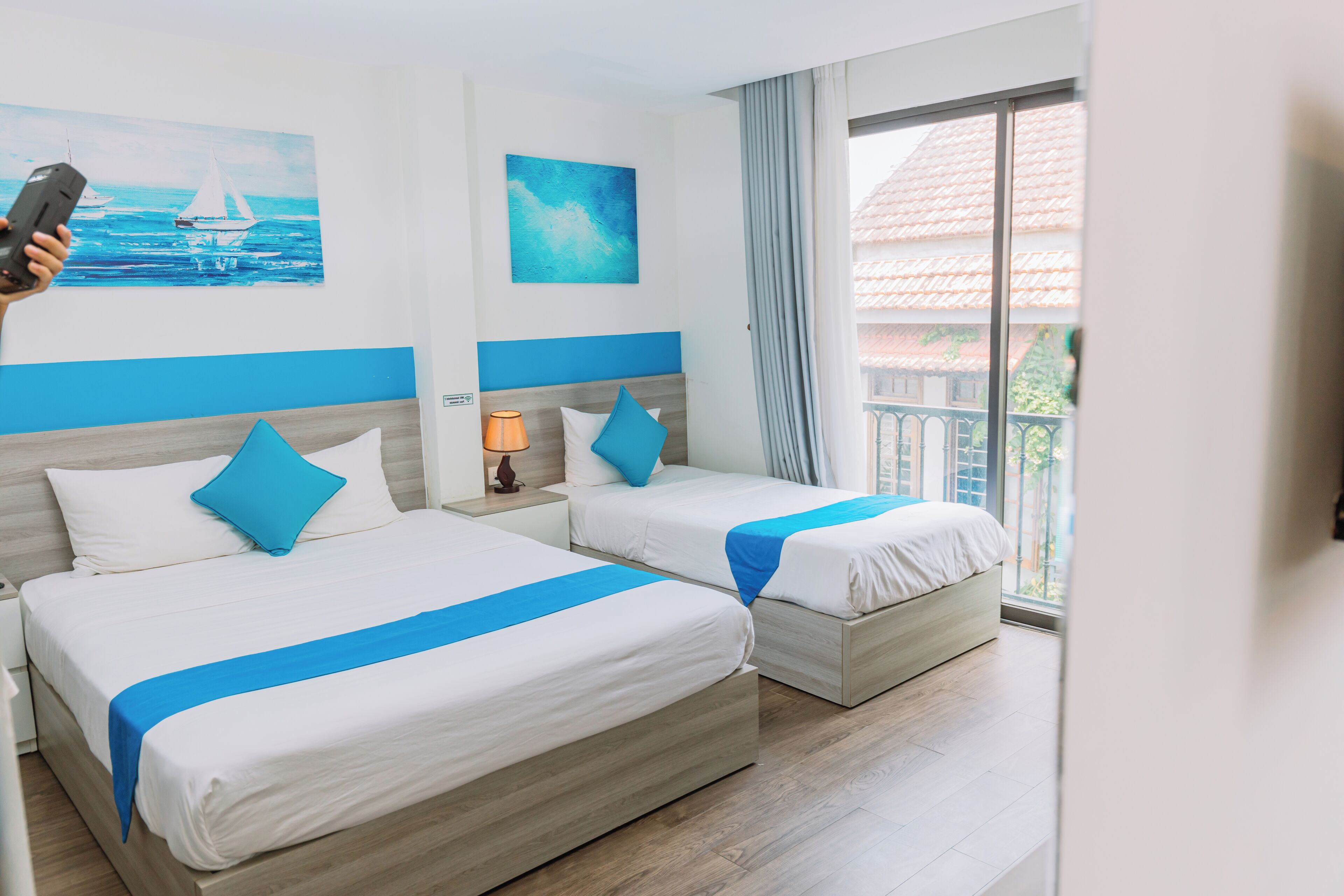 A hotel room with two beds, a large window, and artwork on the walls.