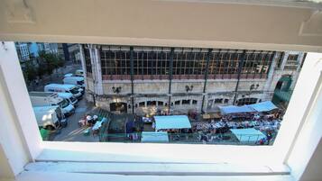 A view from a window overlooking a busy street with market stalls and parked vehicles.