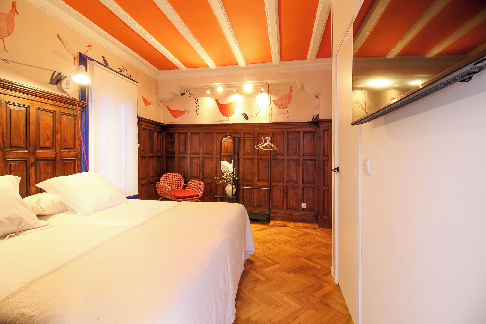 Un dormitorio con una cama grande, un armario de madera y una silla roja.