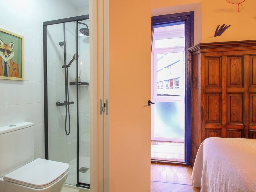 Un baño con cabina de ducha de vidrio, inodoro y un cuadro en la pared.