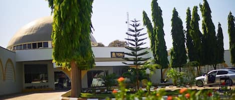 A hotel with a dome structure, a sign reading "DOME HOTEL," and a parking area with a car.