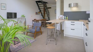 A modern kitchen with white cabinets, a wooden countertop, and a built-in stove. There is a dining area with a table and chairs, and a staircase leading to an upper level. - Flat (max 4 pers) in former farmhouse within walking distance of Workum centre (Workum)