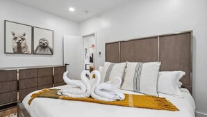 Habitación de hotel con cama, ropa de cama blanca, cabecera marrón y dos cuadros con imágenes de animales en la pared.