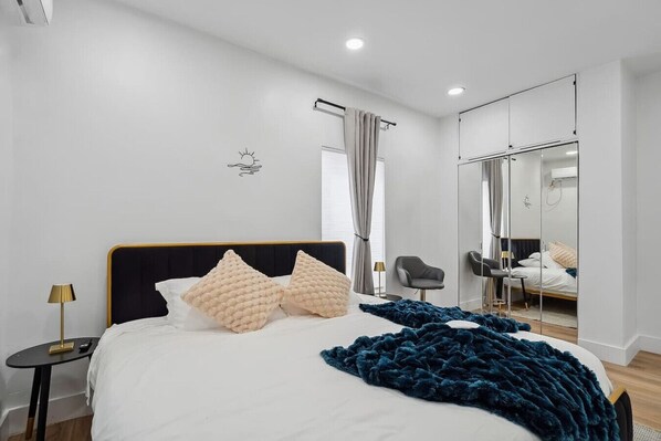 A modern bedroom with a large bed, a mirror, and a small table.