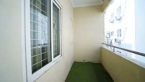 A narrow balcony with a green artificial turf floor, white walls, and a window with a grid pattern. - The Stem (Hyderabad)