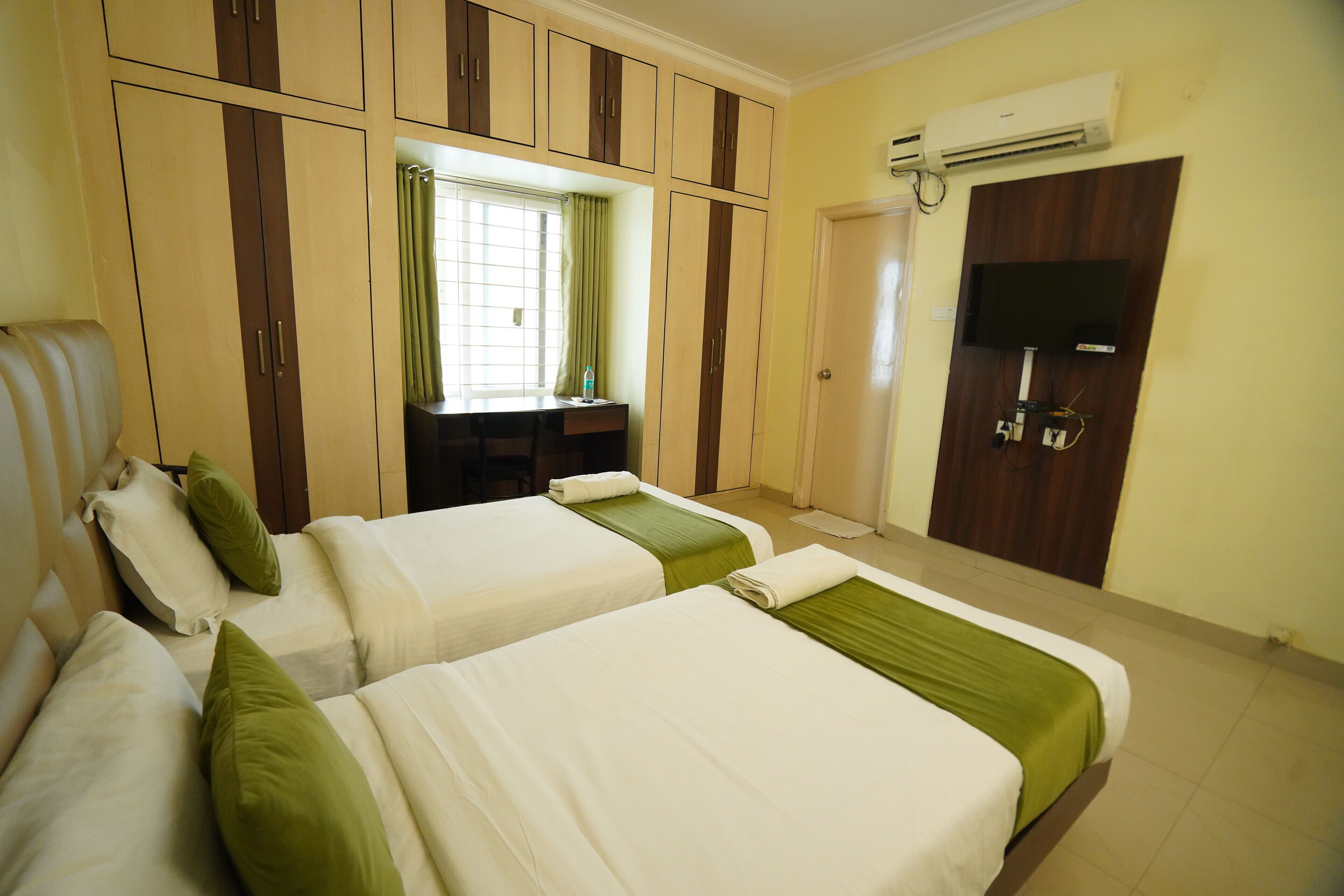 A hotel room with two beds, a desk, a TV, and a wardrobe.