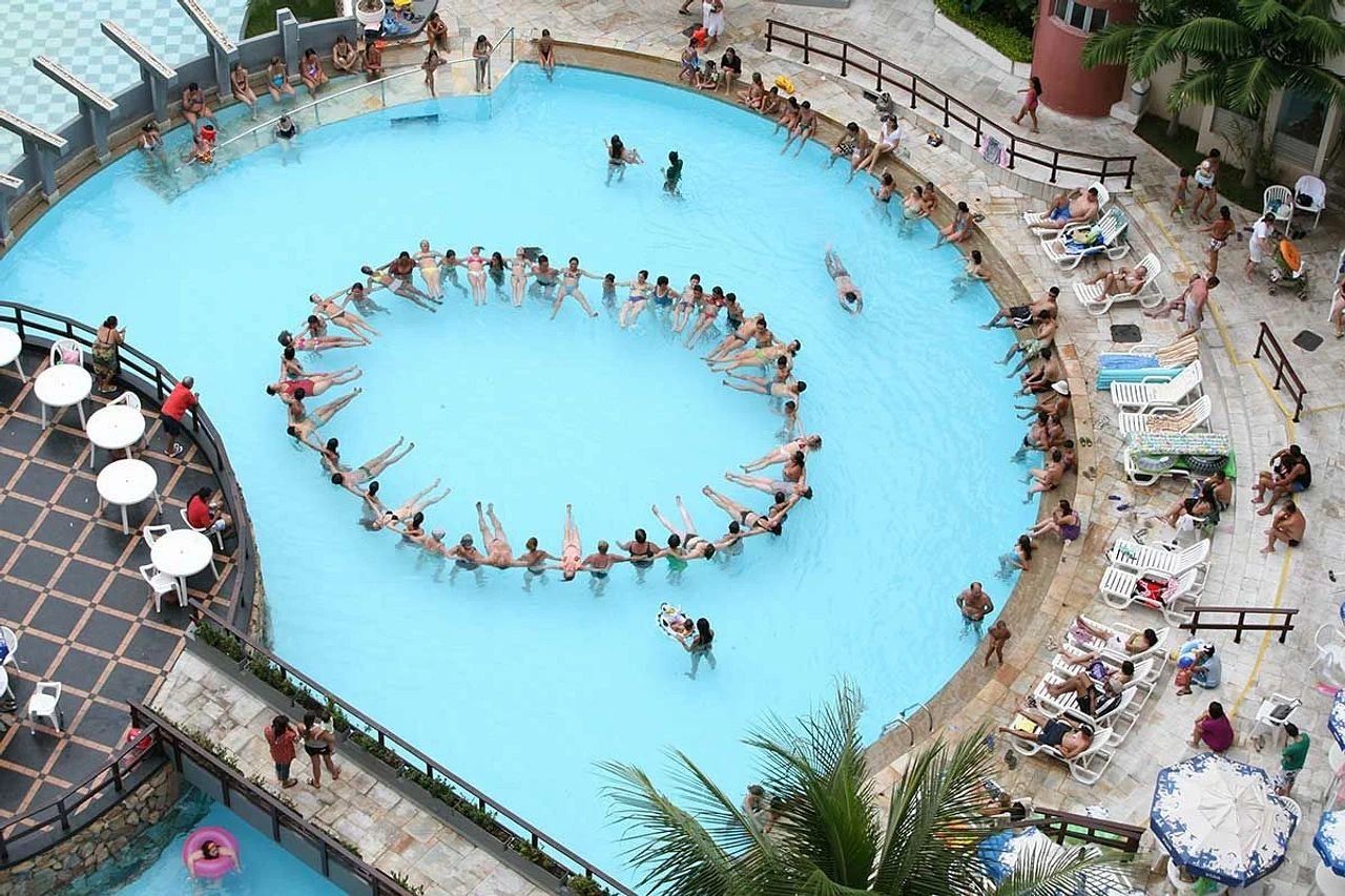 A large circular swimming pool surrounded by lounge chairs and umbrellas.