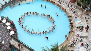 A large circular swimming pool surrounded by lounge chairs and umbrellas.