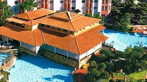 A hotel with multiple swimming pools, a large building with a tiled roof, and surrounding greenery. - Hotel Maravilhoso-Banheira-PiscinaTermal (Caldas Novas)