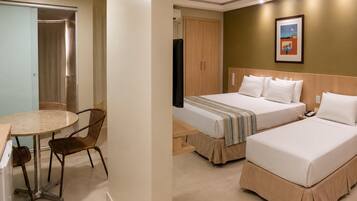 A hotel room with two beds, a desk with a chair, a wardrobe, and a painting on the wall.
