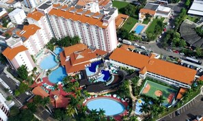 A hotel with multiple swimming pools, a tennis court, and a large building with a red roof. - Hotel Maravilhoso-Banheira-PiscinaTermal (Caldas Novas)
