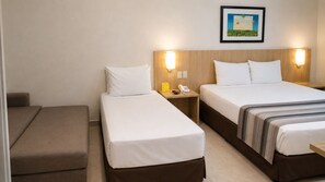 A hotel room with two single beds, a sofa, a bedside table with a phone, and a wall-mounted light fixture. - Hotel Maravilhoso-Banheira-PiscinaTermal (Caldas Novas)