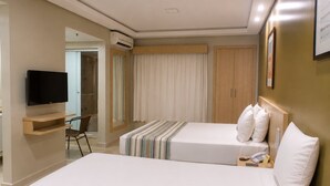 A hotel room with two beds, a TV, a desk, a chair, and a wardrobe. - Hotel Maravilhoso-Banheira-PiscinaTermal (Caldas Novas)