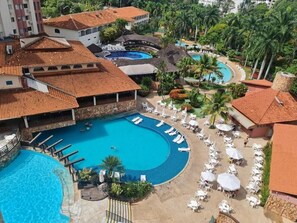 A resort with multiple swimming pools, sun loungers, and palm trees. - Hotel Maravilhoso-Banheira-PiscinaTermal (Caldas Novas)