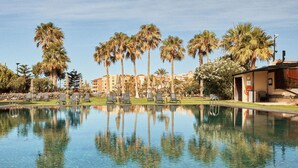 Una piscina cristalina con reflejos de palmeras y un edificio al fondo.