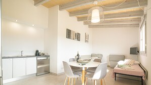 A modern kitchen with a dining area, a sofa, and a bed.