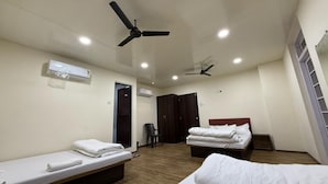 A hotel room with two beds, a ceiling fan, an air conditioning unit, and a wooden floor. - Hotel Marine Line (Mumbai)