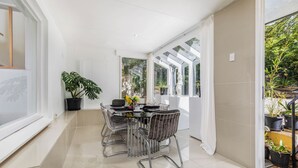 A modern dining area with a glass table, metal chairs, and potted plants. - Architectural Comfy 2B&2B suite with garden view close to lake & Shopping Centre (Yarralumla)