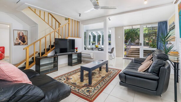 A modern living room with a sofa, a coffee table, a TV, and a staircase. - Architectural Comfy 2B&2B suite with garden view close to lake & Shopping Centre (Yarralumla)