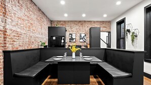 A modern dining area with a brick wall, black furniture, and a wooden floor.