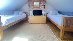 A bedroom with two wooden beds, a TV, and a brick wall.