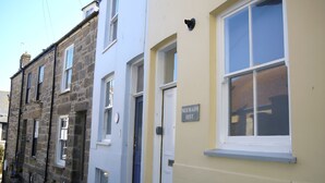 A row of terraced houses with a sign indicating a 'Mermaids Rest' on one of the doors.