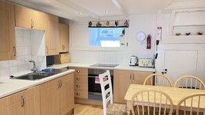 A compact kitchen with wooden cabinets, a sink, a toaster, and a window with a view.
