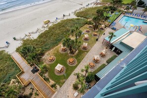 Ein Strandhotel mit Pool, Sitzgelegenheiten im Freien und Blick aufs Meer.