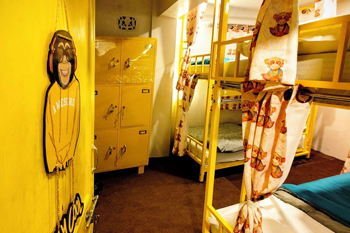 A room with bunk beds, a yellow wall, a sign reading "STAYCO", and a wooden door.