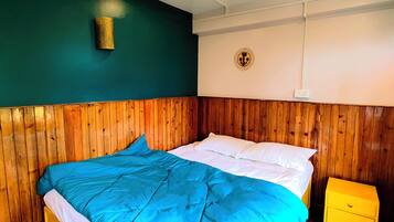Una cama con edredón azul y blanco, cabecera de madera y mesita de noche amarilla.