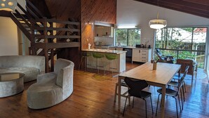 Una cocina moderna con una escalera de madera, un comedor con mesa y sillas, y vistas al exterior.