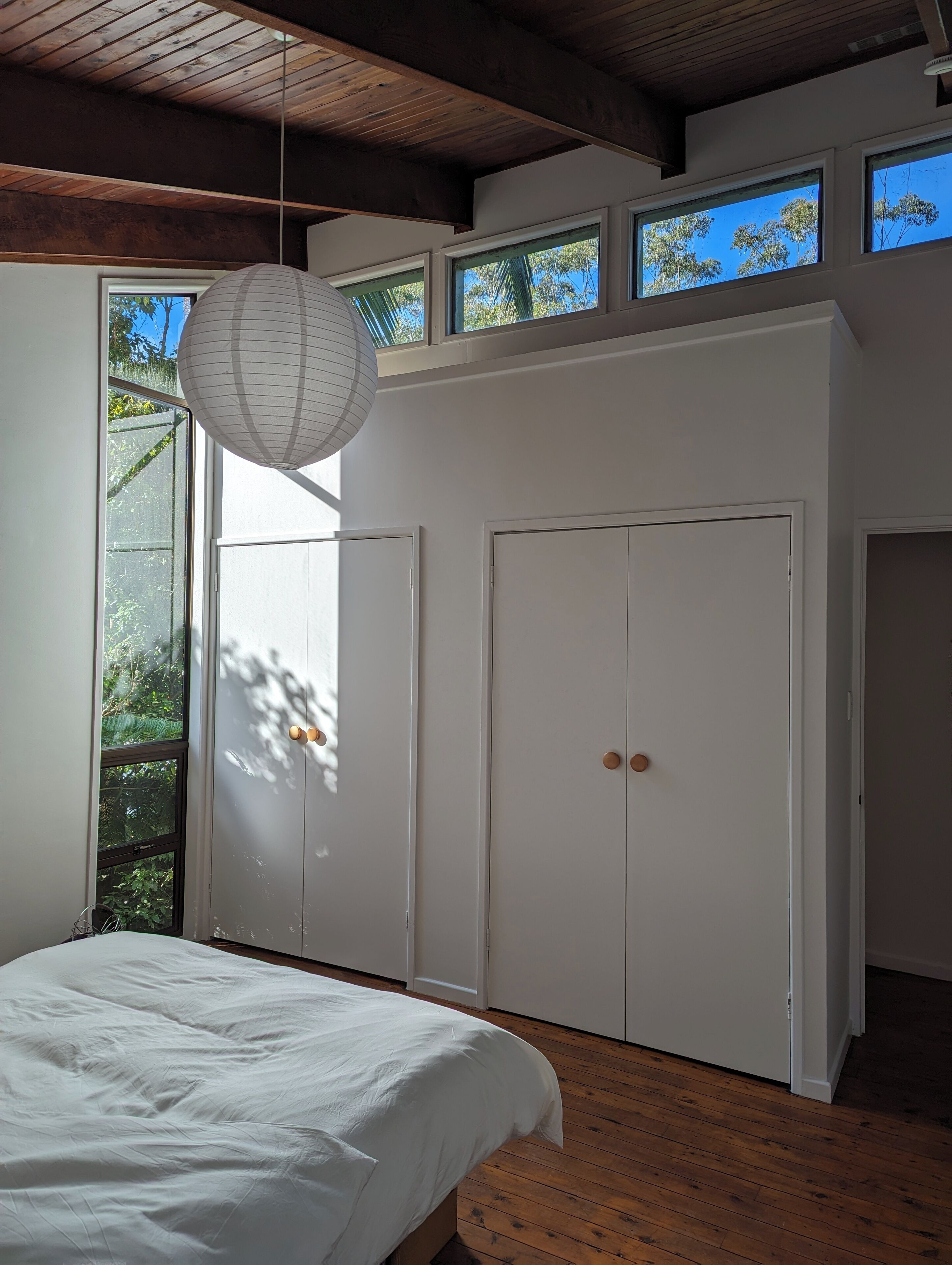 A bedroom with a bed, a hanging light fixture, and a wardrobe.