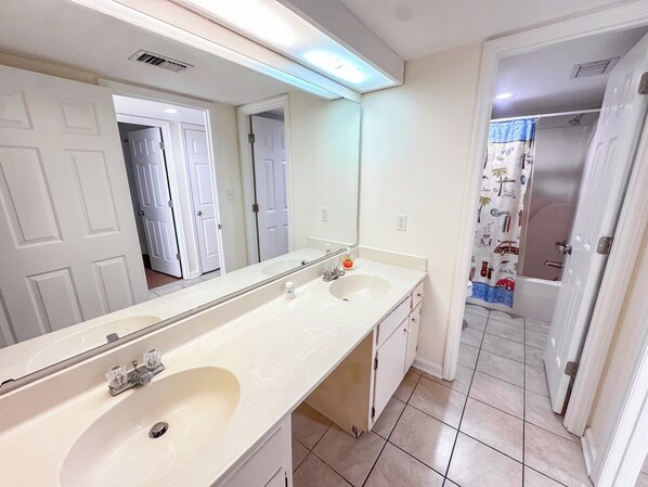 A bathroom with two sinks, a large mirror, and a shower area.