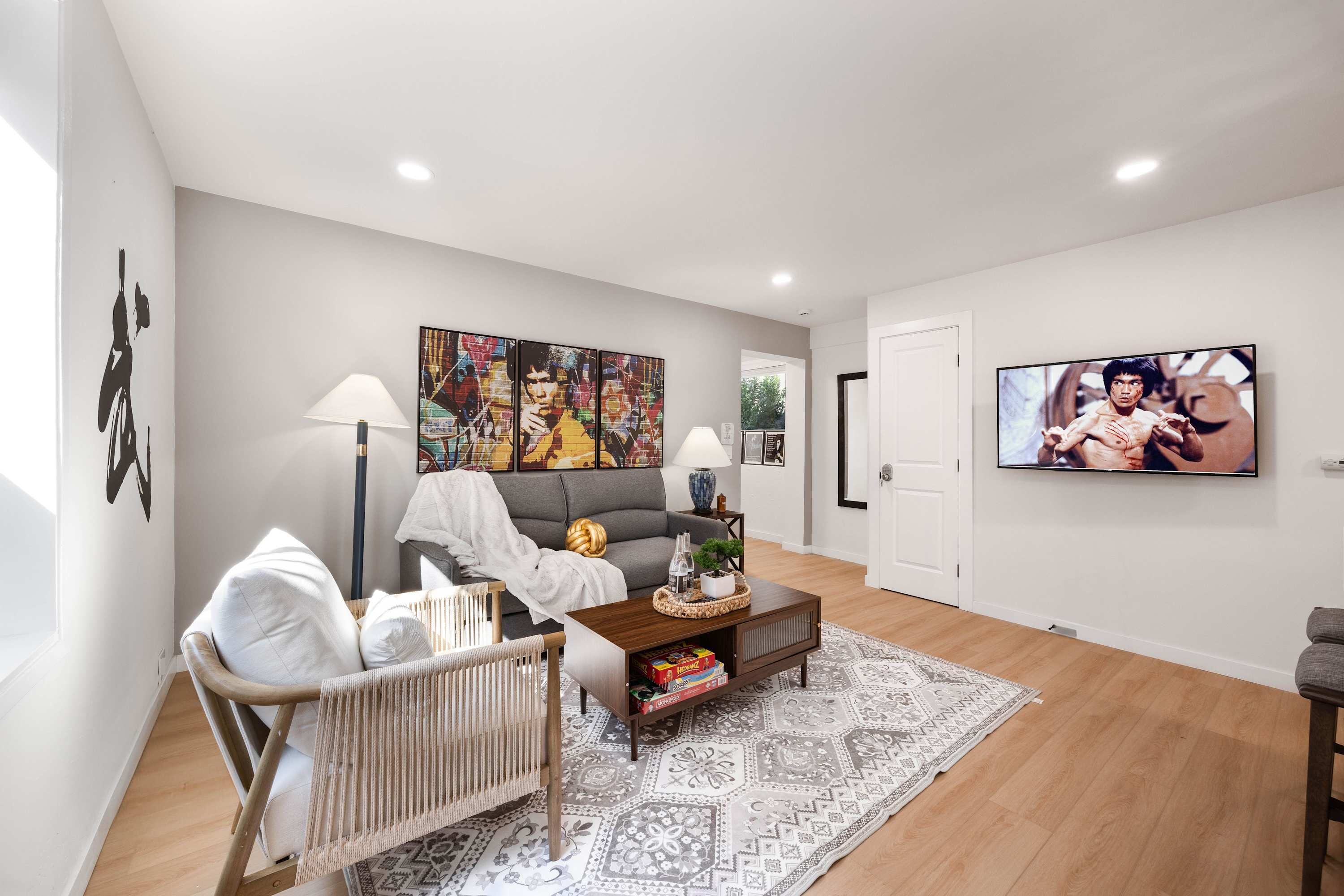 A modern living room with a grey sofa, a wooden coffee table, a patterned rug, and a television on the wall.