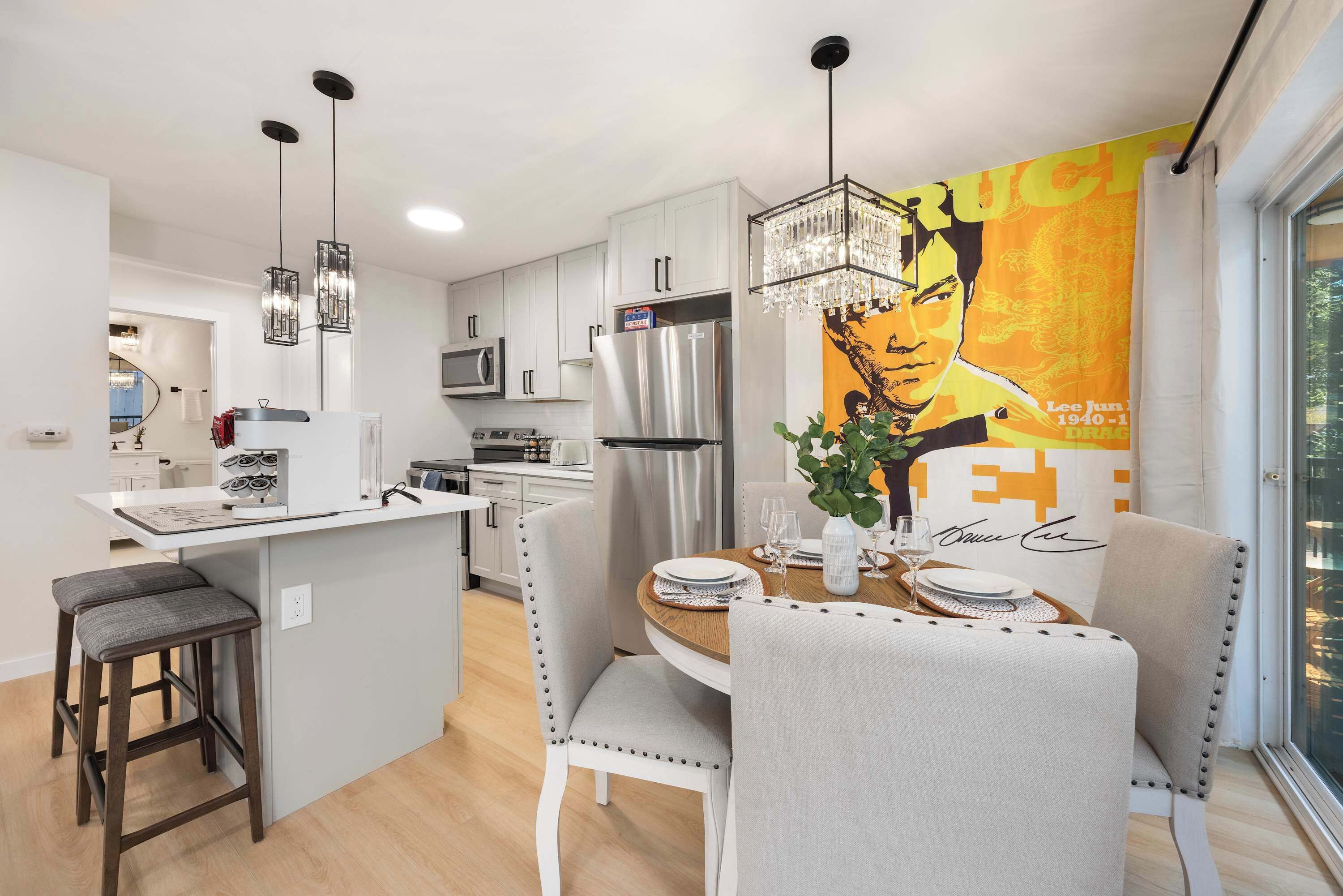 Une cuisine moderne équipée d’appareils électroménagers en acier inoxydable, un coin repas avec une table ronde et une grande affiche accrochée au mur.