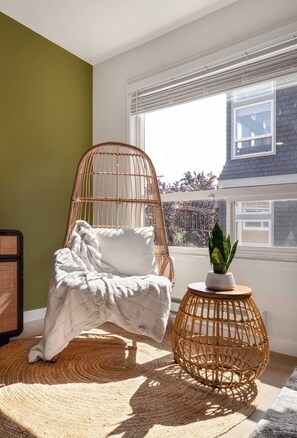  A comfy reading nook bathed in natural sunlight, with a modern woven chair and cozy blanket for ultimate relaxation.