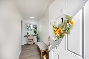A hallway with a bench, a door with a sunflower decoration, and a window with a view of the outside. - Brand New 2BR Condo in Queen Anne, Walk to Space Needle (Seattle)