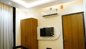 A hotel room with a wooden wardrobe, a desk, a mounted TV, and an air conditioning unit. - Hotel Shakuntla Palace 400 mts to Vishnupad Temple (Gaya)