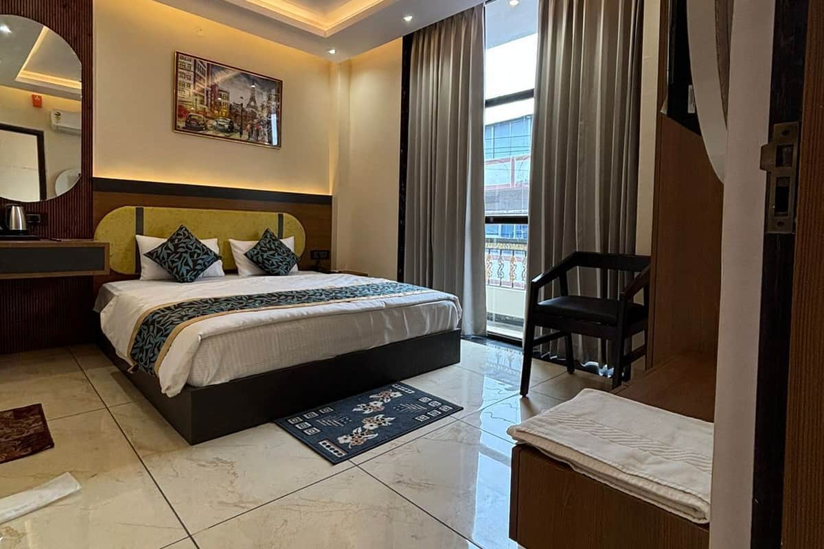 Una habitación de hotel moderna con una cama grande, un ventilador de techo, un cuadro en la pared y vistas al exterior a través de la ventana.