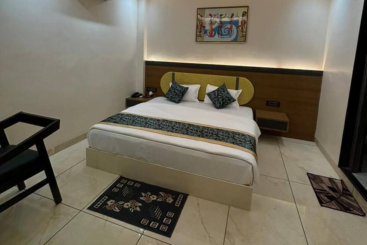 Una habitación de hotel moderna con una cama, ventilador de techo, unidad de aire acondicionado, mesita de noche, escritorio y silla.