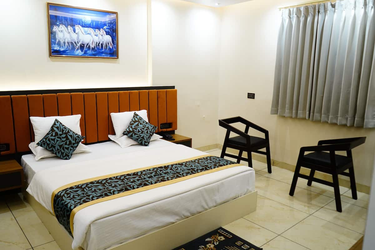 Una habitación de hotel con una cama grande, dos mesitas de noche, un escritorio y una silla.