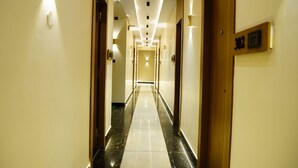 A hotel hallway with a long, straight layout, multiple doors, and wall-mounted light fixtures. - Hotel Shakuntla Palace 400 mts to Vishnupad Temple (Gaya)
