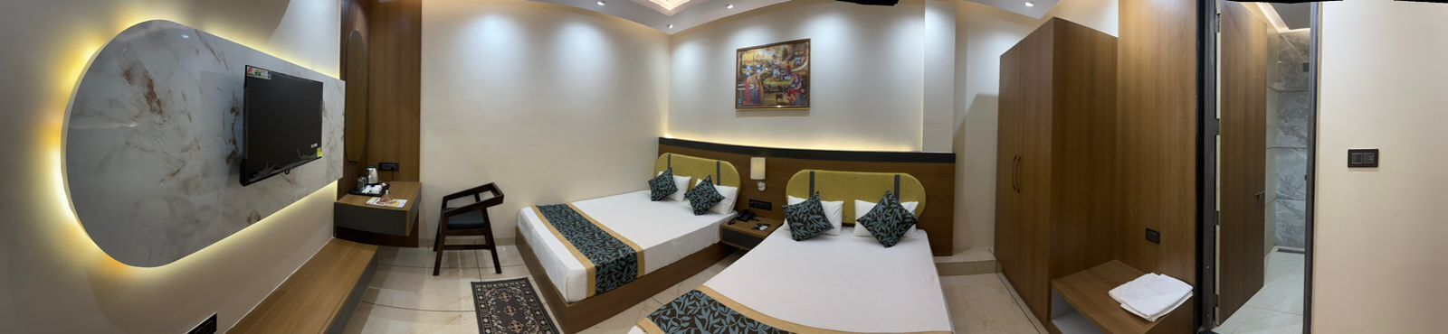 A modern hotel room with a large TV, two beds, a desk, and a shower area.